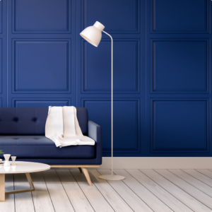 Modern living room with a navy blue paneled wall, a dark blue sofa, white floor lamp, and light wood flooring